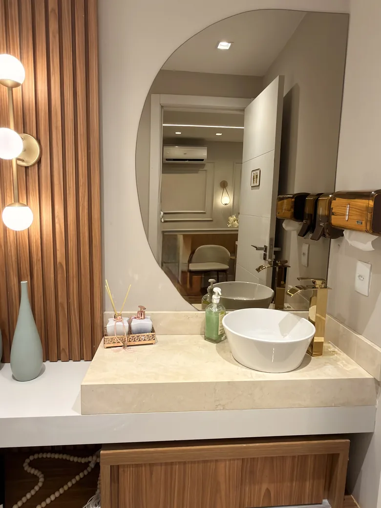 Lavabo com cuba branca, bancada clara e espelho arredondado